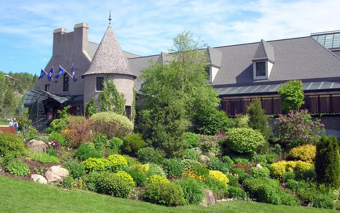 Casino de Charlevoix in La Malbaie, a grey-roofed building with a round turret behind landscaped rock gardens